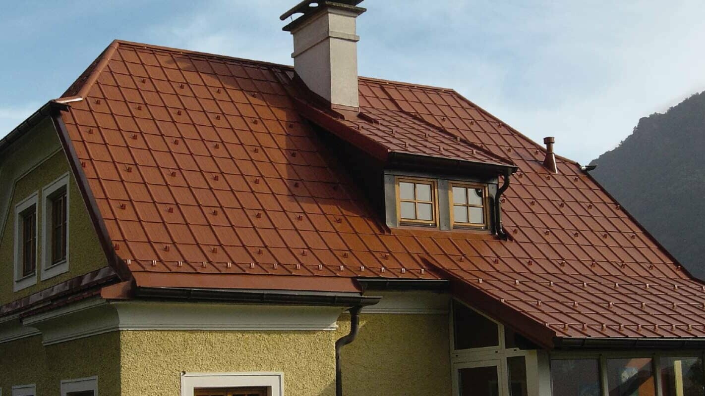 Bostadshus med halvvalmat tak och takkupa med nyrenoverat tak med PREFA takplattor i tegelrött