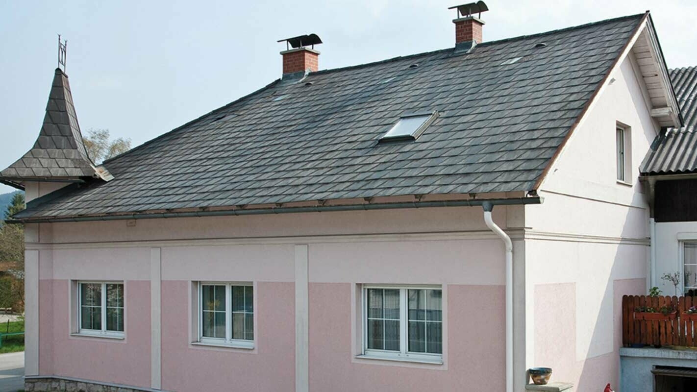Hus före takrenovering med PREFA takplattor i Österrike - tidigare Eternit fibercement och litet torn, rosa fasad