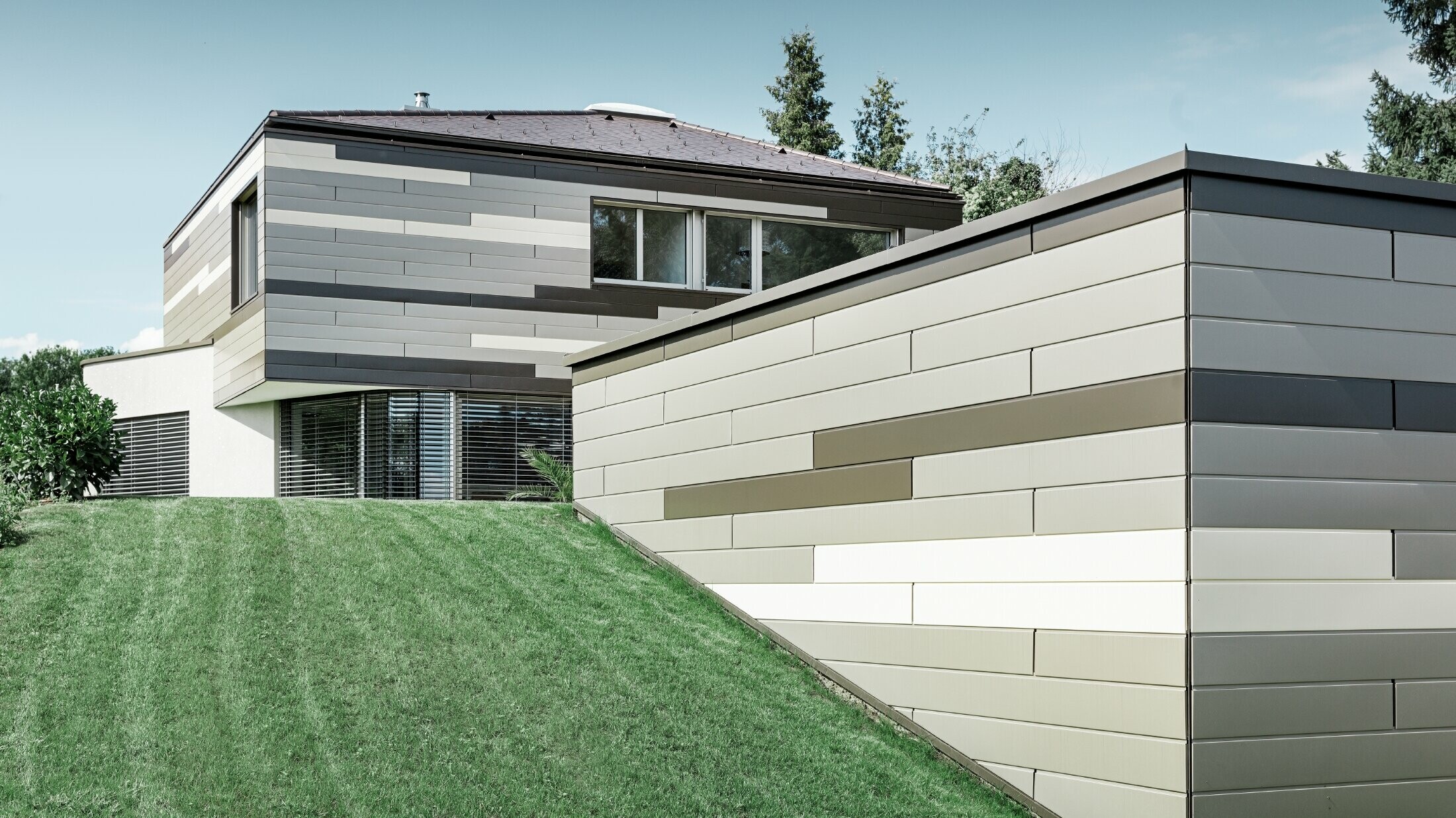 Modernt enfamiljshus med plantak och täckt terrass med en individuellt utformad aluminiumfasad av fasadpaneler i brunt, brons och elfenben från PREFA