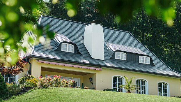 Nyrenoverat bostadshus tak med PREFA takshingel i antracit med rundade takkupor (fladdermuskupor) och vit skorsten. 