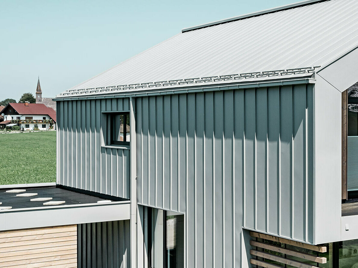 Enfamiljshus med sadeltak, med PREFALZ på tak och fasad; för takavvattningen används PREFA rektangulär ränna med PREFA kvadratrör i specialfärgen patinagrå.