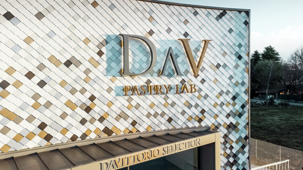 Företagsbyggnad tillhörande DAV Pastry Lab i Bergamo med väggrombfasad strösslad med färgerna P.10 brun, brons, P.10 mörkgrå, mayaguld, valsblank, P.10 prefavit och P.10 renvit 