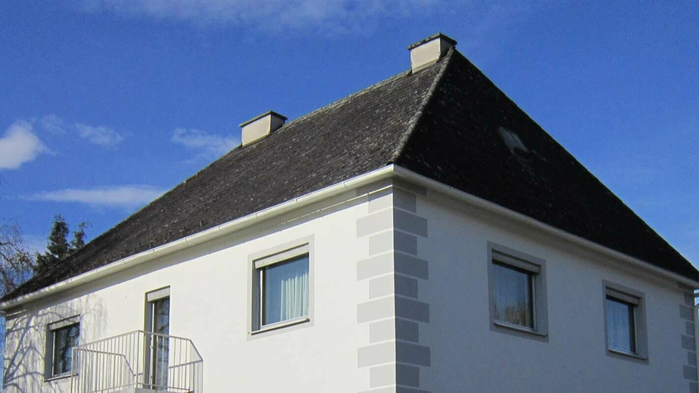 Hus med valmat tak innan takrenovering med Prefalz och PREFA-takplattor i Österrike