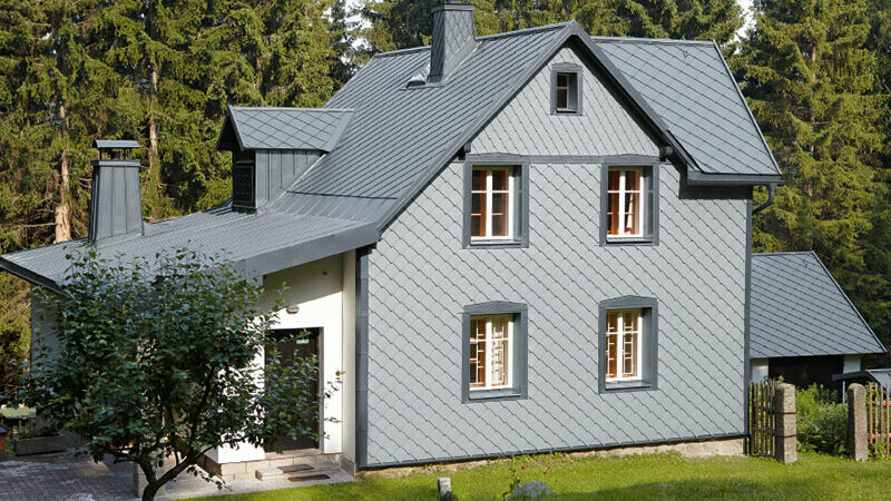 Enfamiljshus i skogsområde med väderbeständig PREFA aluminiumfasad i ljusgrå.