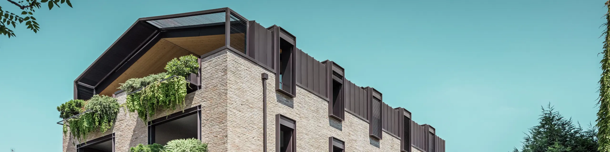 Modernes Wohngebäude in Italien mit PREFALZ-Aluminiumdach in P.10 Haselnussbraun, Backsteinfassade und hängenden Gärten – nachhaltige Architektur für die Sanierung dieses Gebäudes.