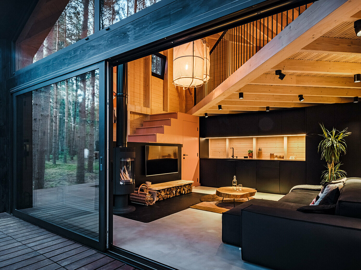 Seitenansicht eines Ferienhauses mit einem schräg verlegten Prefalz-Dach. Die umgebende Natur spiegelt sich im verglasten Bereich wider.