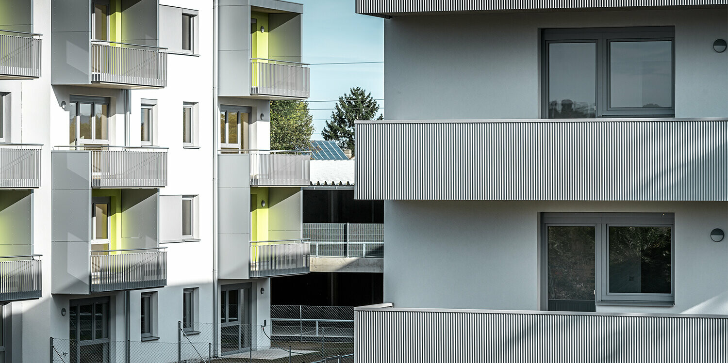 Nahaufnahme der Balkone der Glanzstoffsiedlung in St. Pölten, Niederösterreich. Die Balkone sind mit dem langlebigen PREFA Zackenprofil in der Farbe Silbermetallic verkleidet. Die Beschattung zeigt deutlich, wie sich das Zackenprofil durch Sonneneinstrahlung optisch verändert.