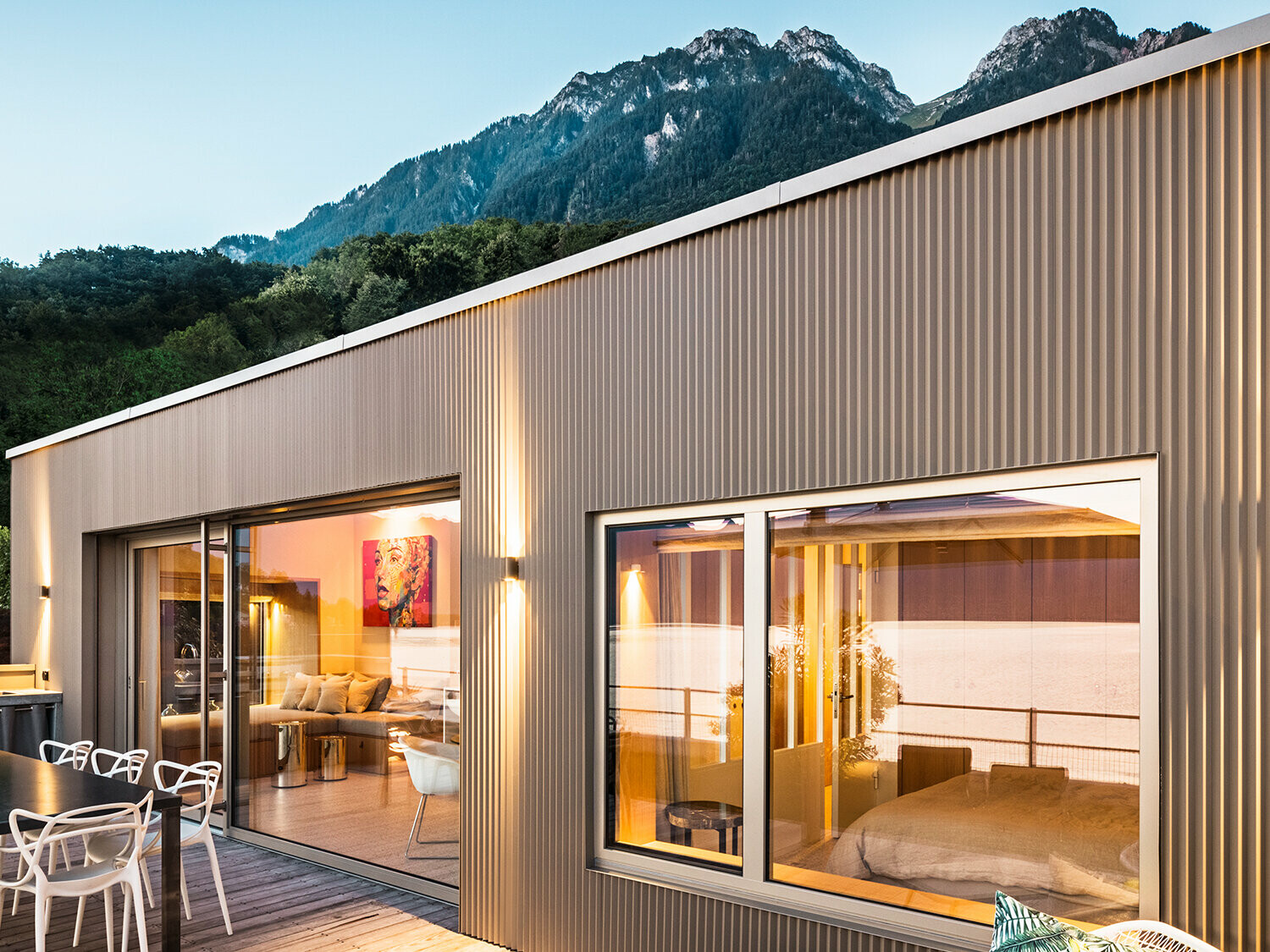 Vy av terrassen och del av interiören under kvällstid.