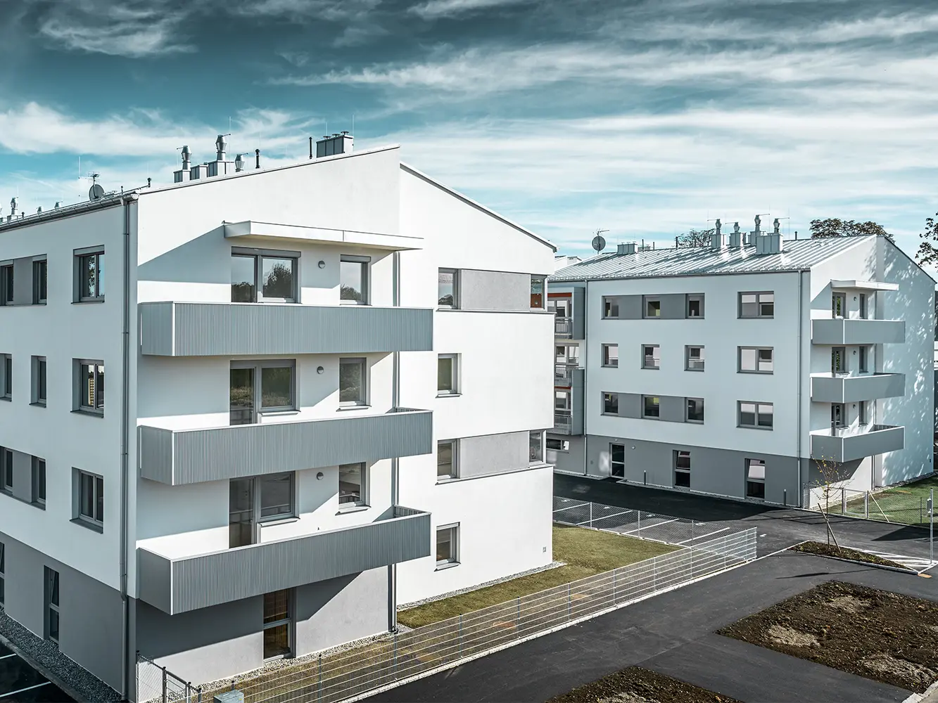 Modern bostadskomplex med vit fasad och balkonger med PREFA-sicksackprofil i silvermetall