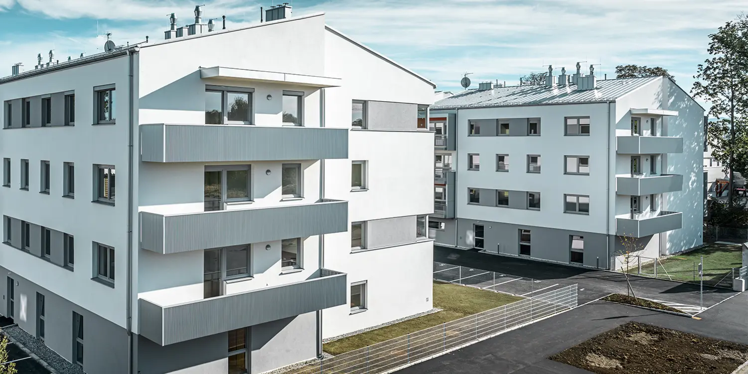 Modern bostadskomplex med vit fasad och balkonger med PREFA-sicksackprofil i silvermetall