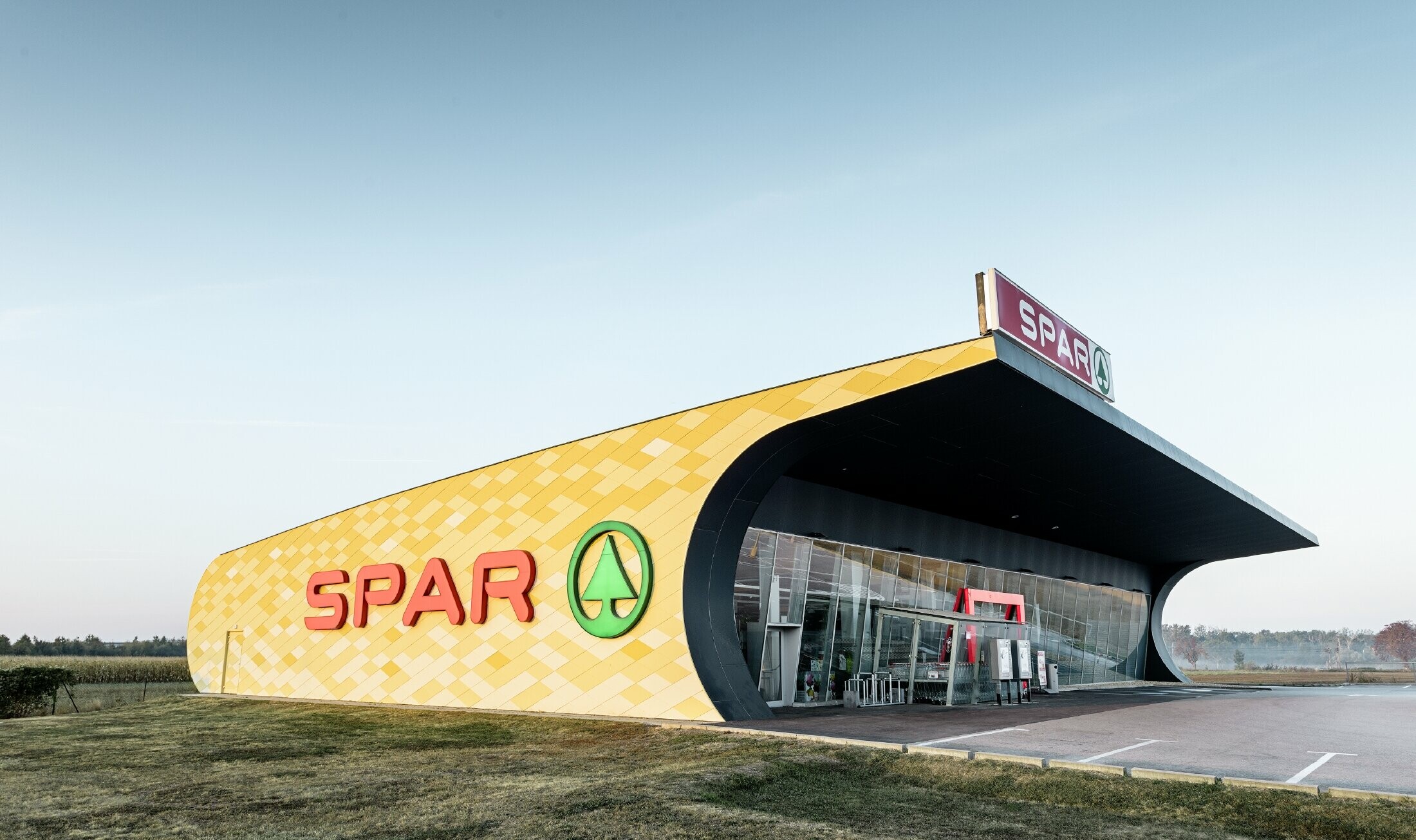 Spar-butik med aluminiumfasad med gulorangefärgade rutor och Spar-logotyp