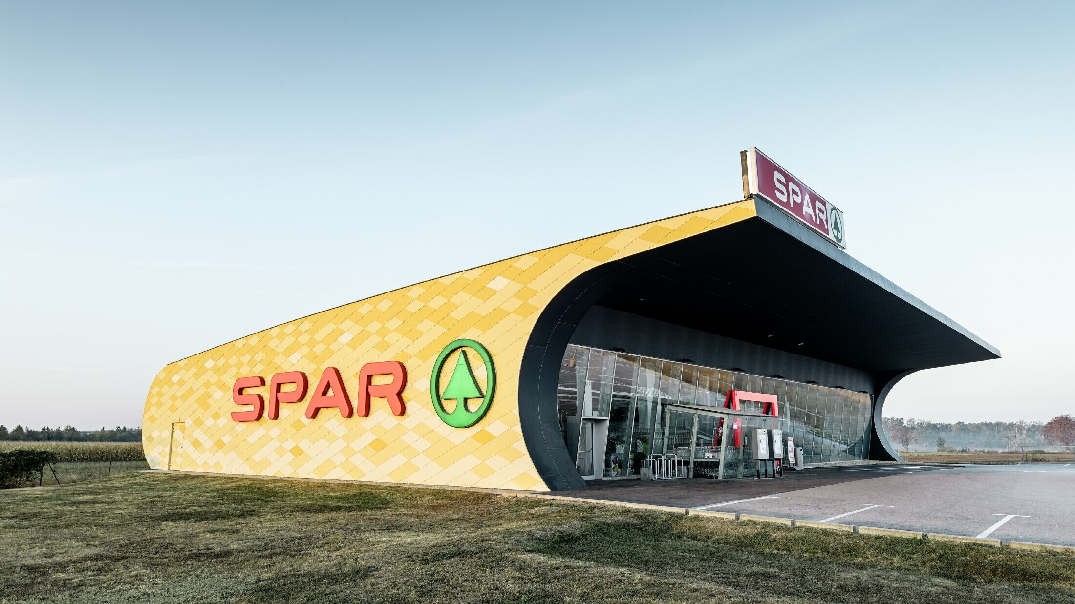 Spar-butik med aluminiumfasad med gulorangefärgade rutor och Spar-logotyp