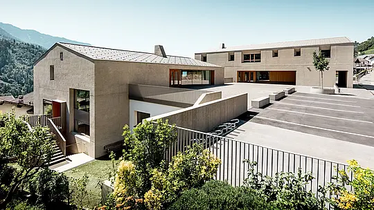 Das Bildungszentrum Riffian in Südtirol zeigt zwei markante Baukörper mit PREFA Dachrauten 44 × 44 in P.10 Bronze vor alpiner Kulisse. Die präzise Aluminiumdeckung betont klare Linien, schützt langlebig und wetterfest und verbindet Kindergarten, Volksschule und sonnigen Schulhof zu einem modernen Architekturensemble.