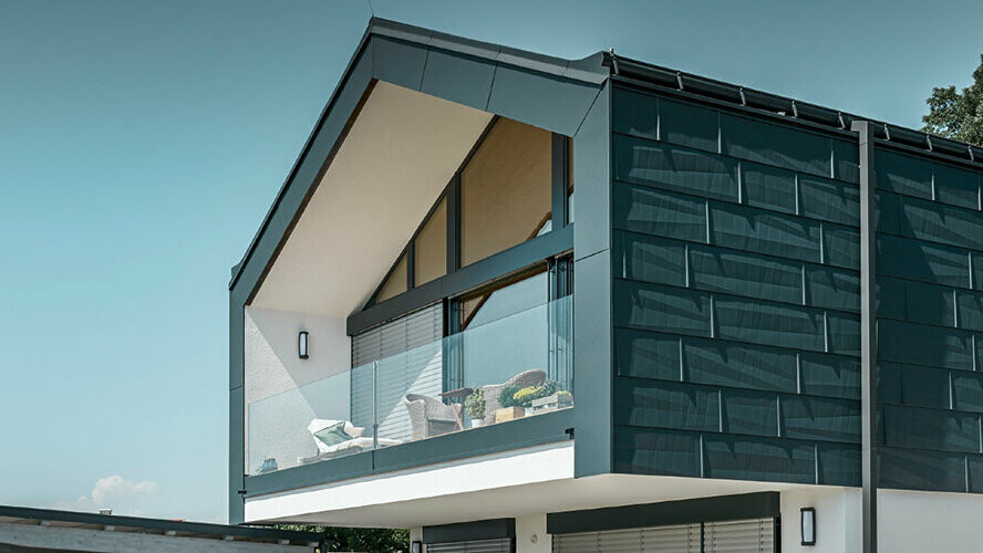 Fasadbeklädnad på övervåning med PREFA fasadpanel FX.12 i P.10 antracitgrå. PREFA robusta fyrkantrör används som stuprör.