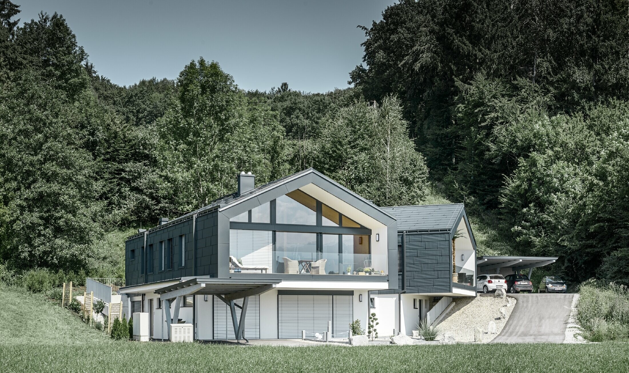 Modernt flerfamiljshus med en stor fönsterfront, tak och fasad är täckta med tak- och fasadpanelerna FX.12 från PREFA i antracitgrått