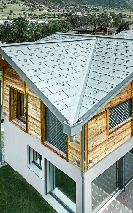 Schweizisk stuga med aluminiumtak från PREFA. Här användes takplattan R.16 i stengrått På den övre våningen monterades en rustik träfasad.