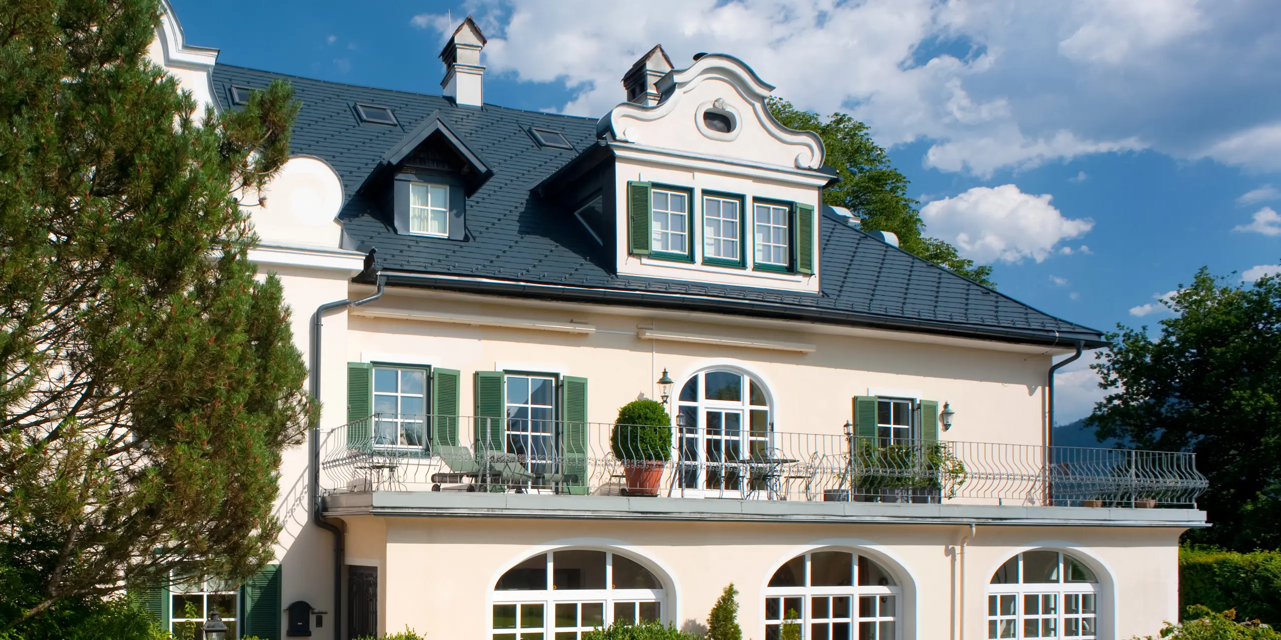 Eine dreistöckige Villa in Bad Aussee, Österreich, mit einem PREFA Dachsystem aus Aluminium. Für die große Dachfläche mit Gauben wurde die vielseitige PREFA Dachschindel in der Farbe P.10 Anthrazit gewählt.