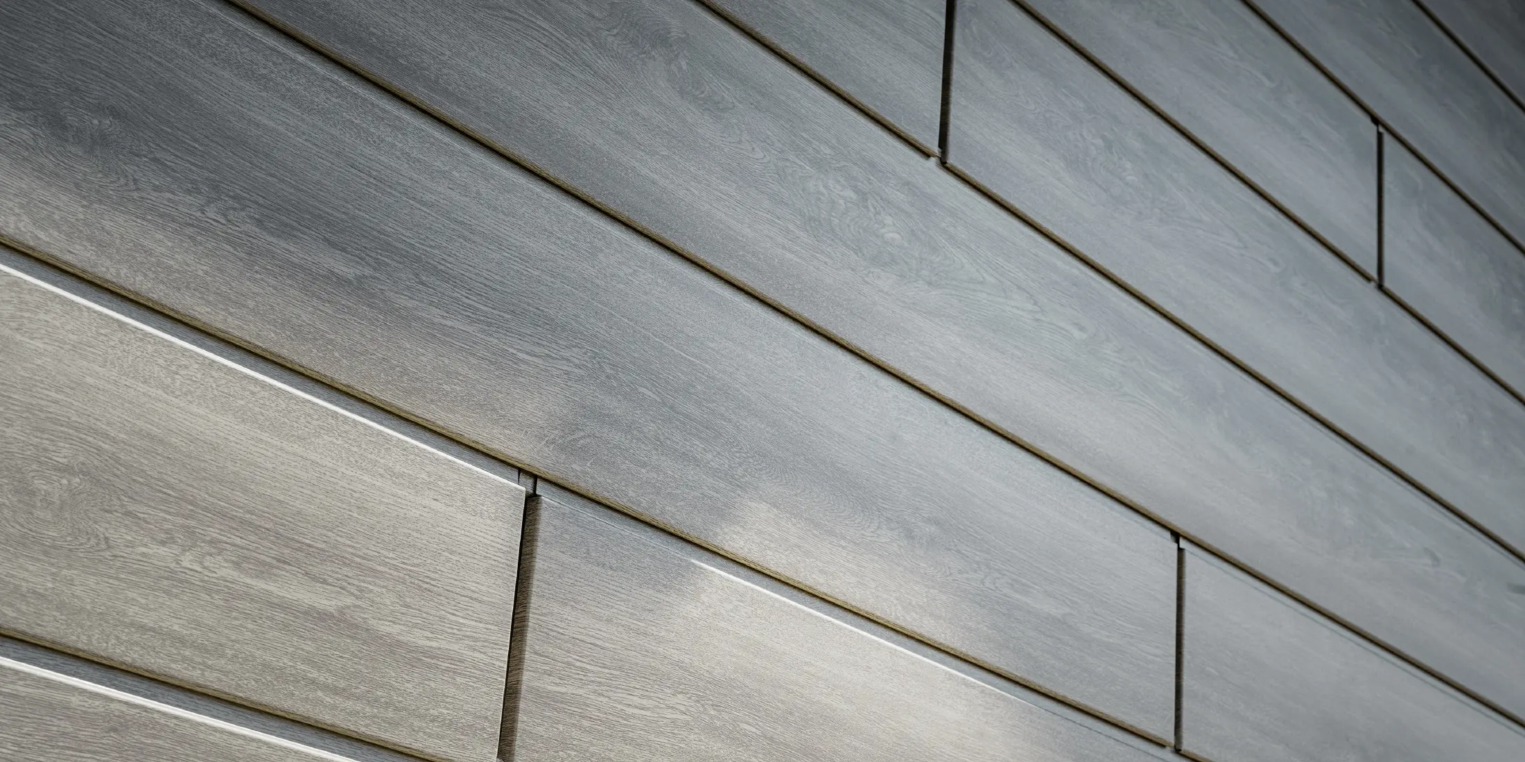 Närbild på PREFA Siding aluminiumfasad, aluminiumpanelerna har lagts horisontellt och har träutseende – beige grå ek.