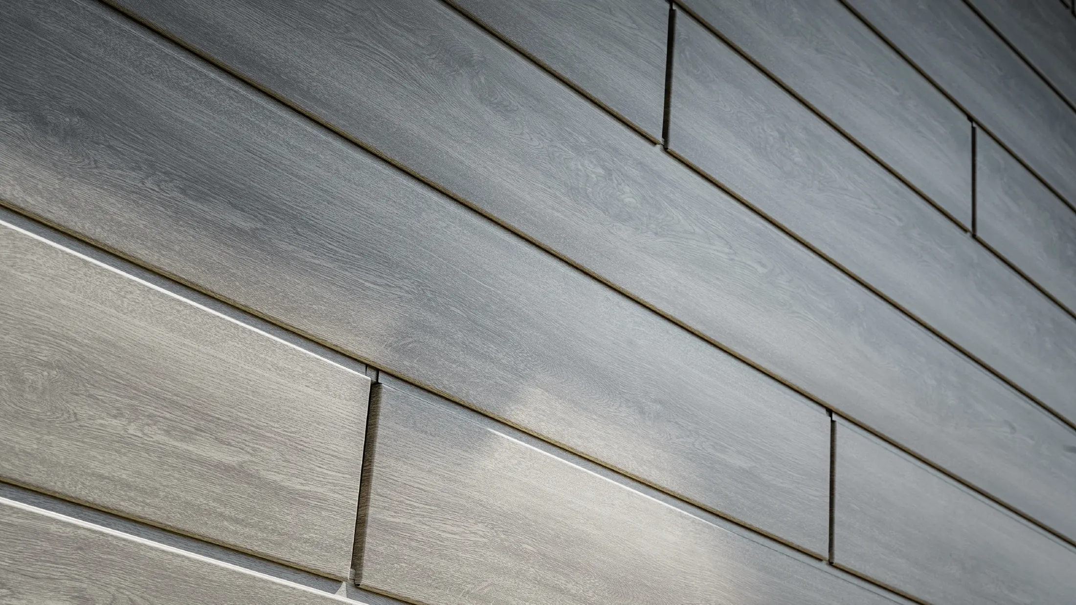 Närbild på PREFA Siding aluminiumfasad, aluminiumpanelerna har lagts horisontellt och har träutseende – beige grå ek.
