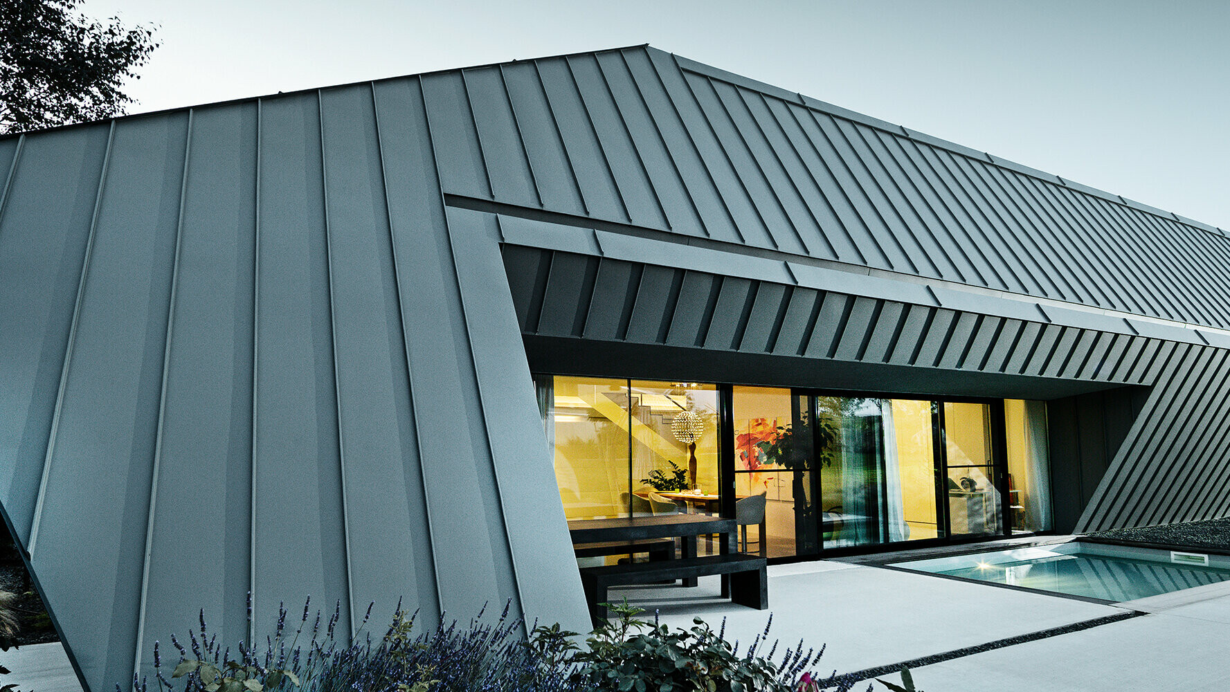 Nybyggt enfamiljshus med tak och -fasad av aluminium från PREFA i färgerna P.10 antracit och P.10 ljusgrå.