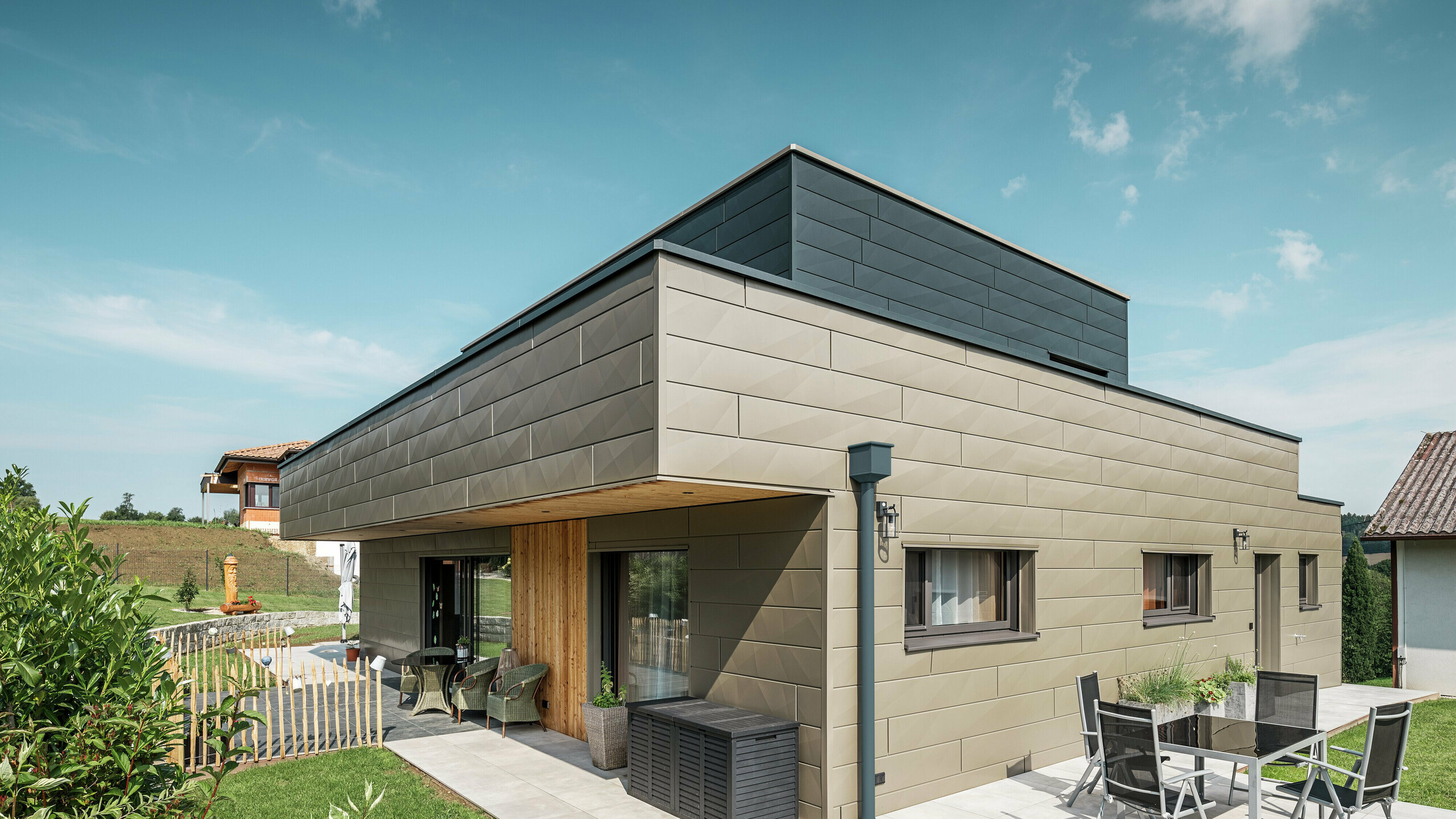 Här visas en villa i Wippenham med en tvåfärgad fasad av Fasadpanel.X i färgerna P.10 Prefabrons och P.10 Anthracite.