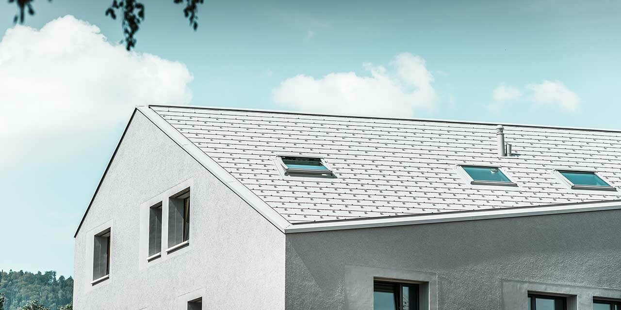 Flerfamiljshus med sluttande takfot och vit takpanel FX.12.