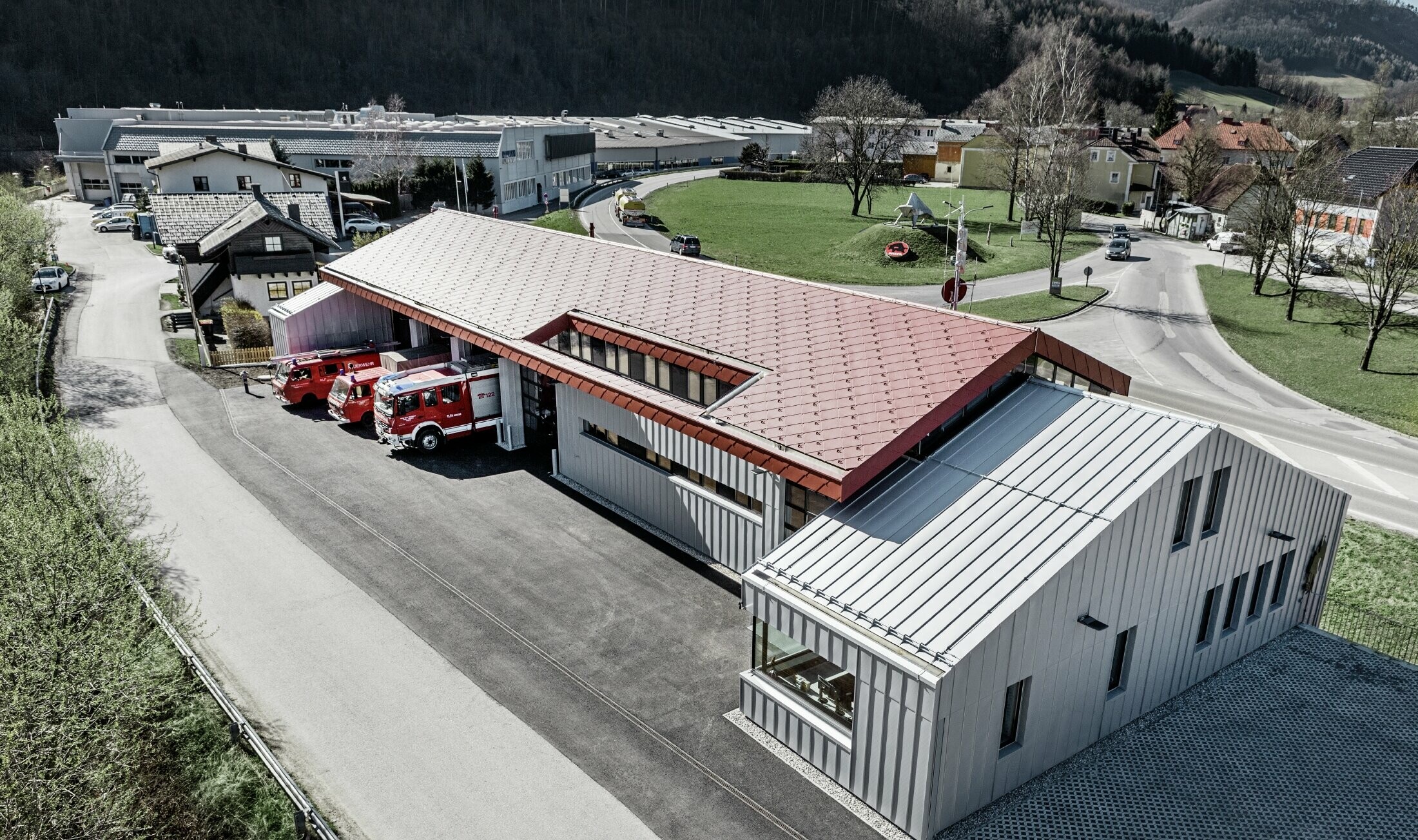 Ett flygfoto av den operativa brandkåren i Marktl/Lilienfeld. Den vänstra delen av byggnaden kläddes helt både på tak och fasad med romb 44 i oxidrött. Den högra delen fick ett aluminiumskal med Prefalz i silvermetallic.