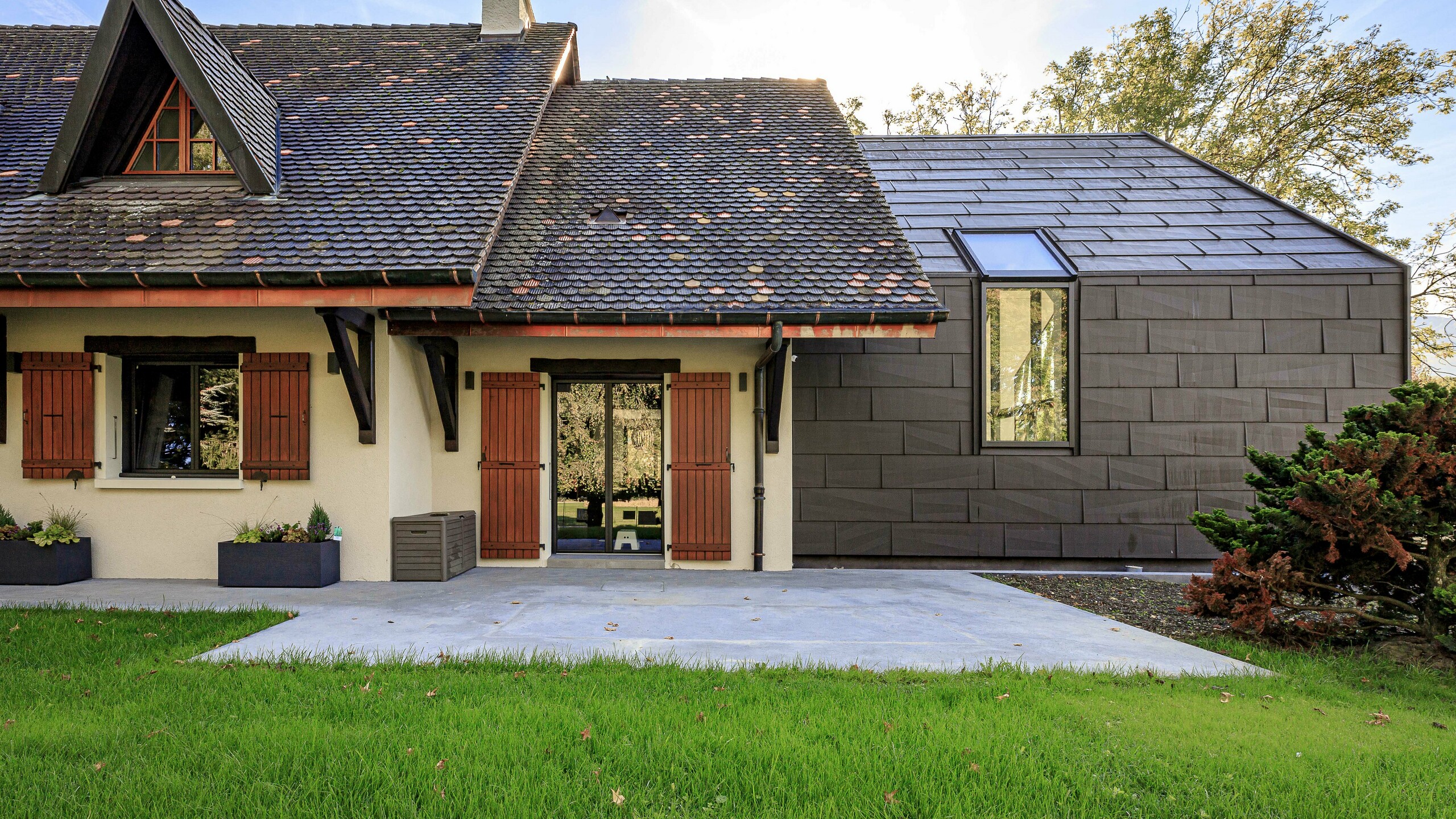 PREFA Dach- und Fassadenpaneele FX.12 in P.10 Braun als kontrastreiches Designelement auf dem Zubau eines Einfamilienhauses in Lully