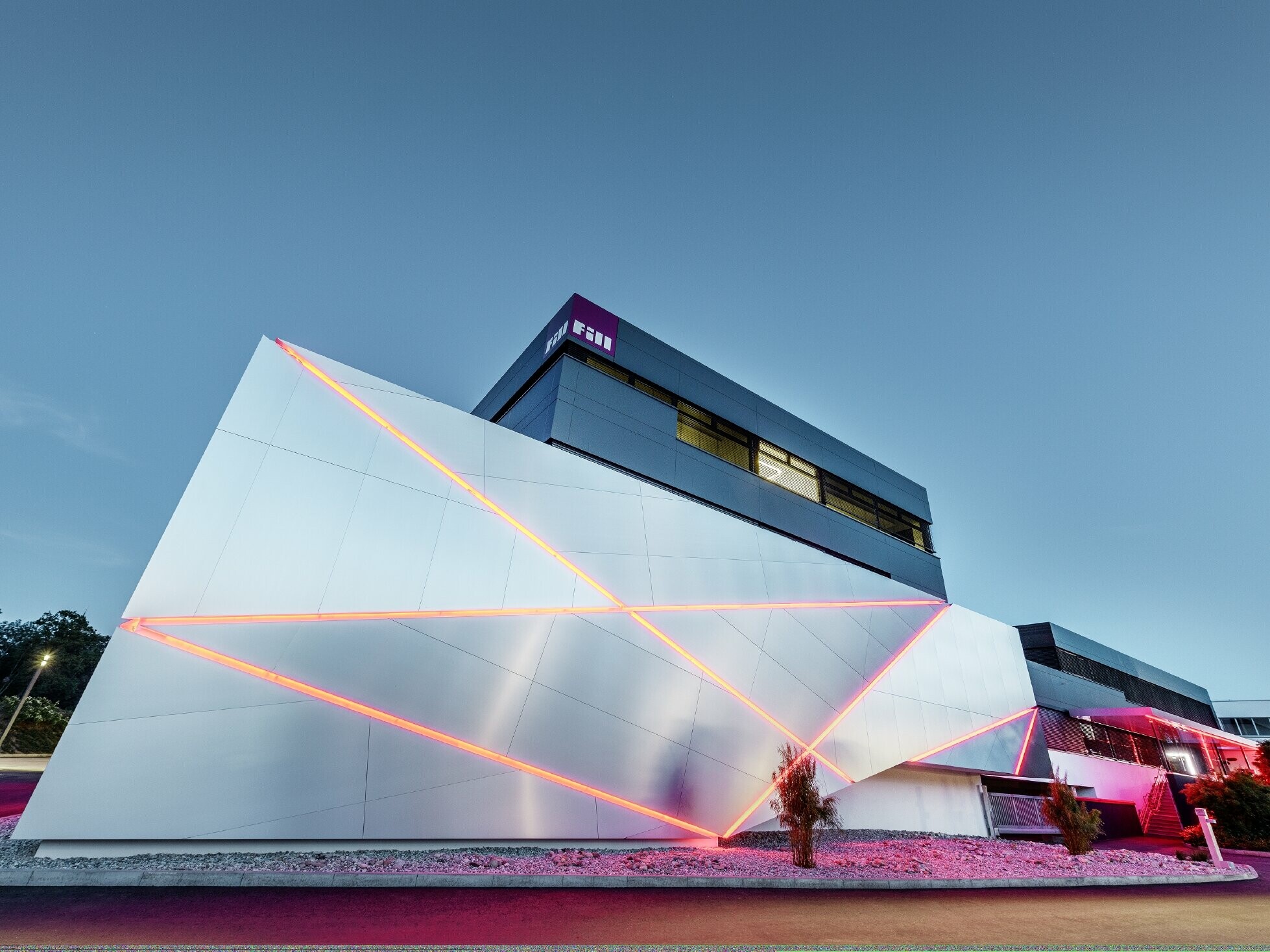 Fill företagsbyggnad med en futuristisk fasad av samverkansplattor i borstad aluminium och bakgrundsbelysta fogar