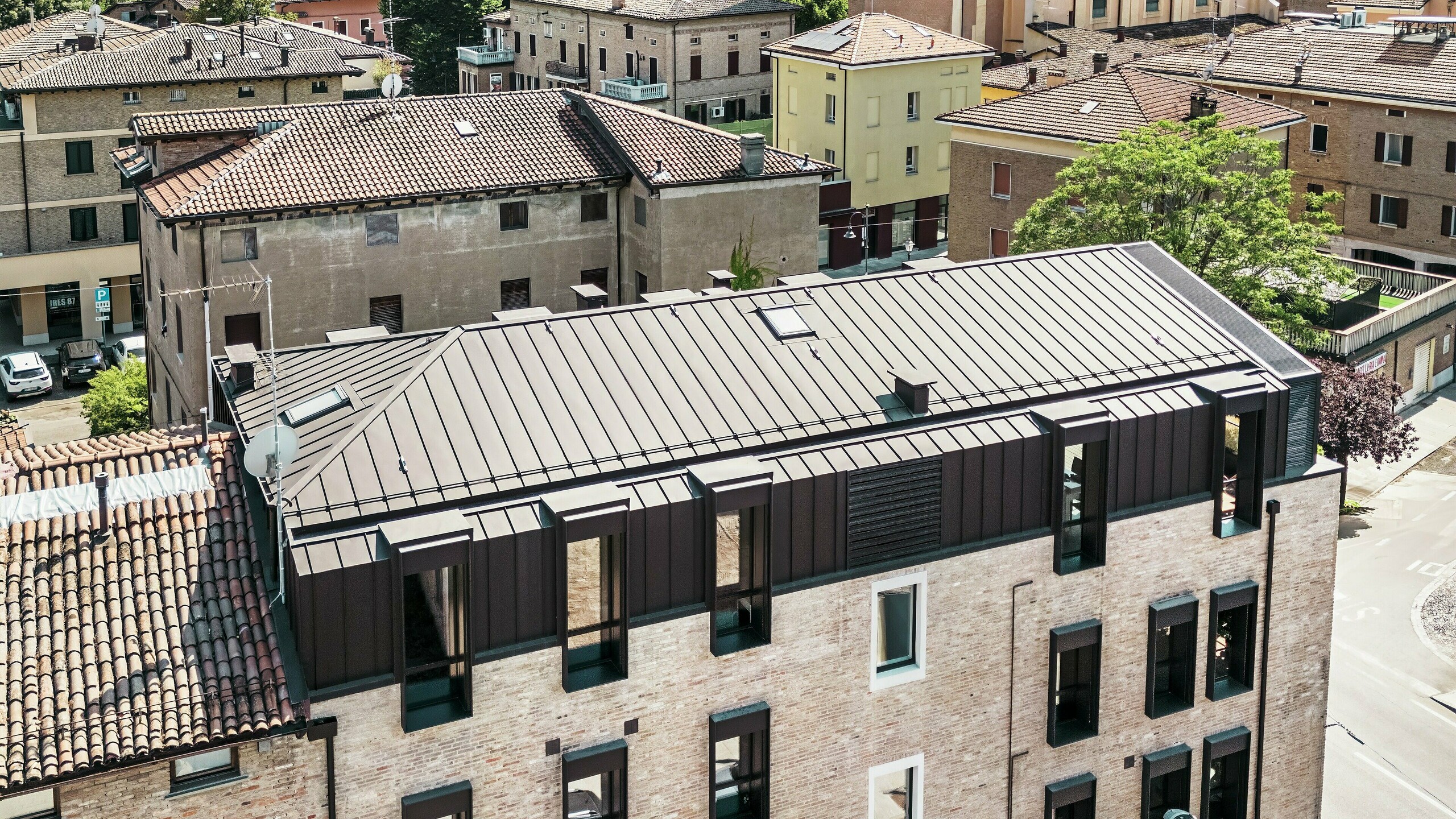 Modernisiertes Backsteinhaus in Italien mit PREFALZ Aluminiumdach in der Farbe P.10 Nussbraun – ästhetische Verbindung von traditioneller Ziegelarchitektur und moderner, langlebiger Dachlösung