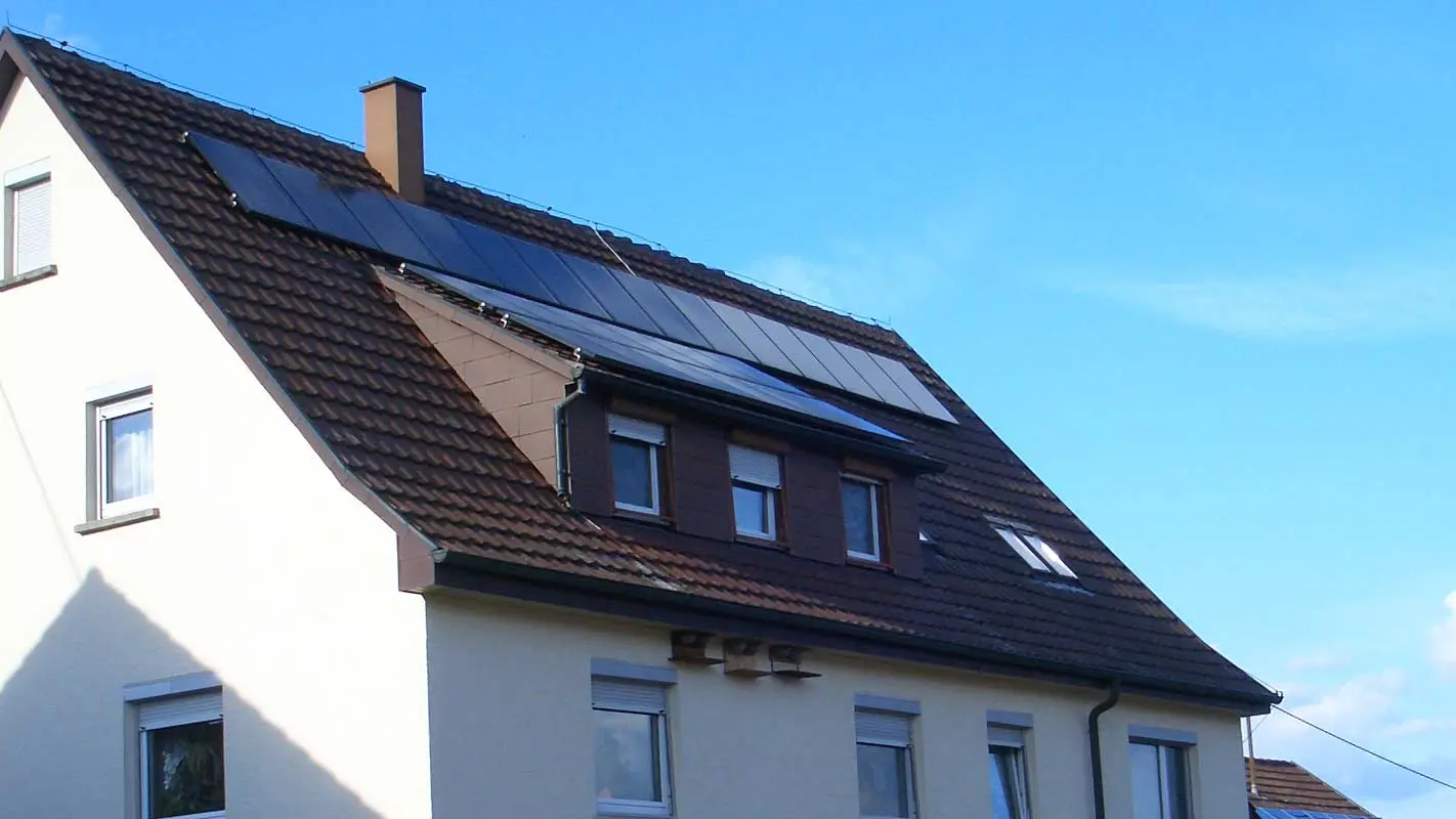 Bostadshus med tegeltak som behöver renovering; Taket har en takkupa och ett solcellssystem.