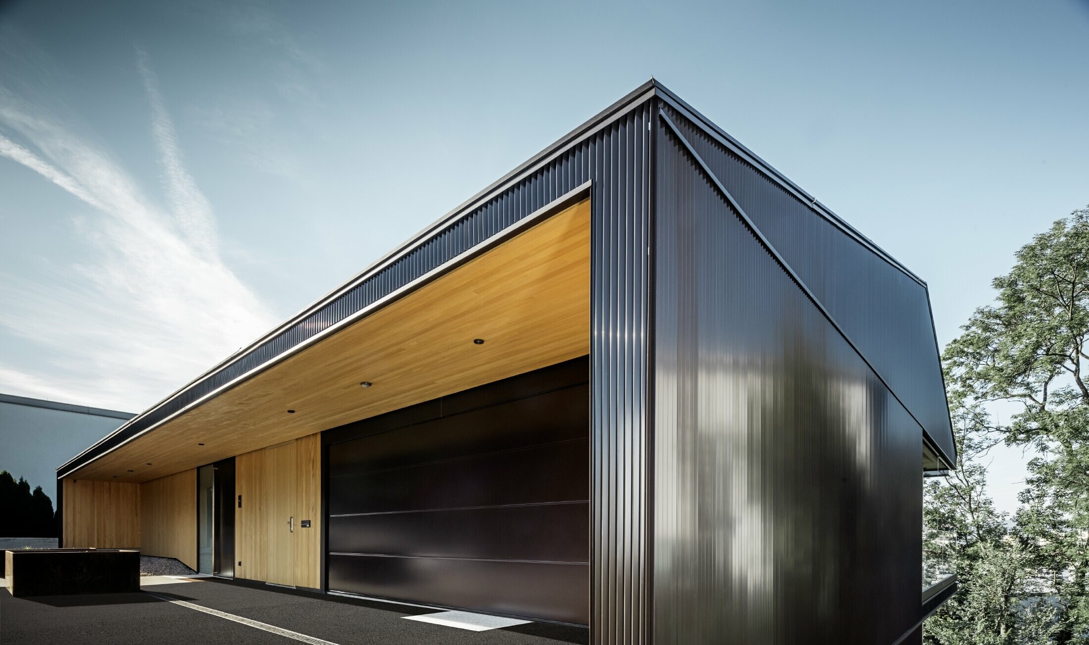 Garageingång i ett enfamiljshus, fasaden är täckt med mörkbrun PREFA sicksackprofil. 