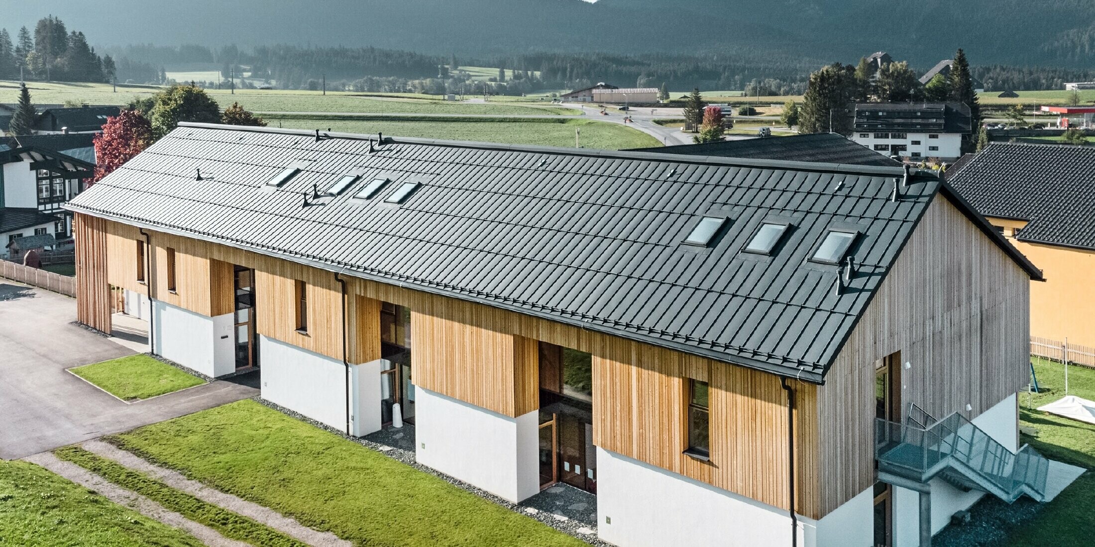 Uteförskola i Bad Mitterndorf med stort PREFALZ-tak i P.10 antracit och träfasad