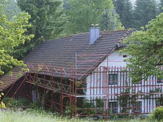 Stugan med sitt gamla tak (med byggställning) före takrenoveringen med PREFA takshingel.
