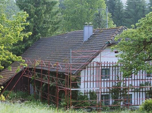 Stugan med sitt gamla tak (med byggställning) före takrenoveringen med PREFA takshingel.