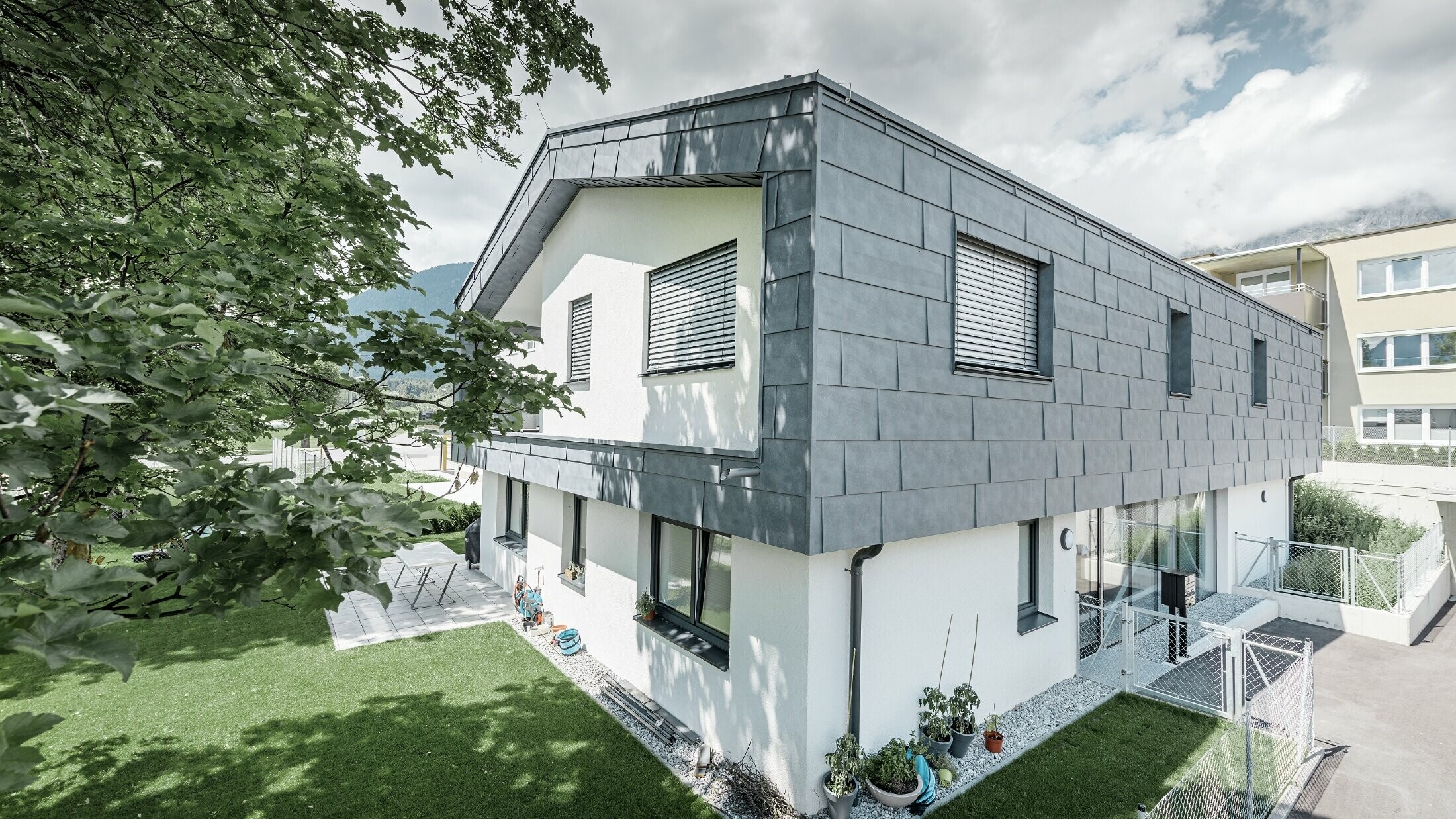 Modern utbyggnad av ett bostadshus med plant sadeltak och utan taköverhäng. Fasadbeklädnaden gjordes med PREFA fasadpanel FX.12 i stengrått.