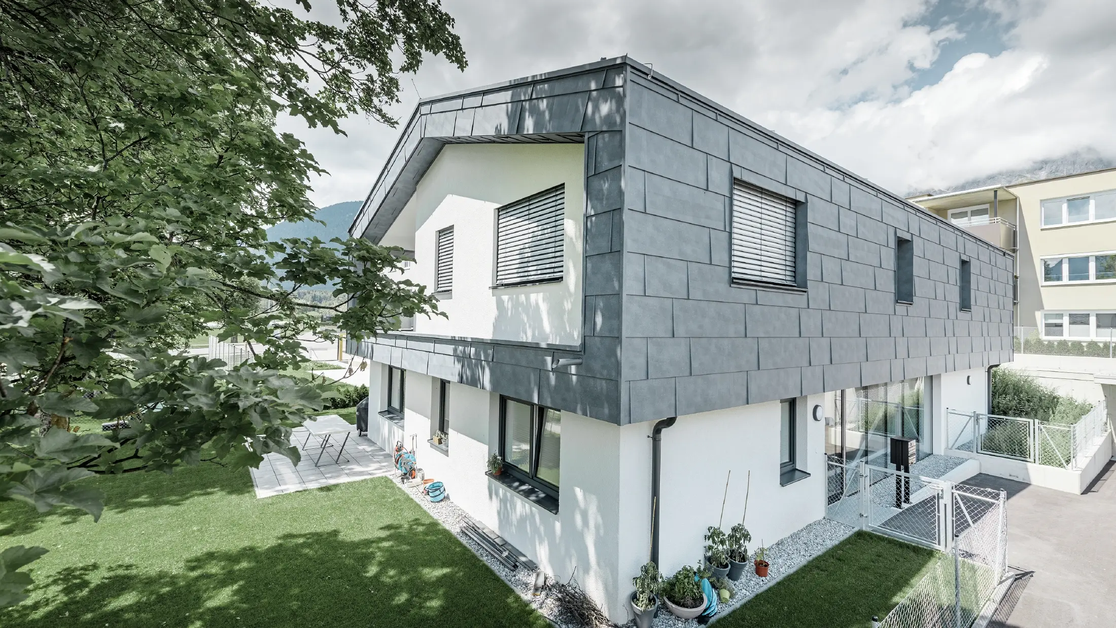 Modern utbyggnad av ett bostadshus med plant sadeltak och utan taköverhäng. Fasadbeklädnaden gjordes med PREFA fasadpanel FX.12 i stengrått.
