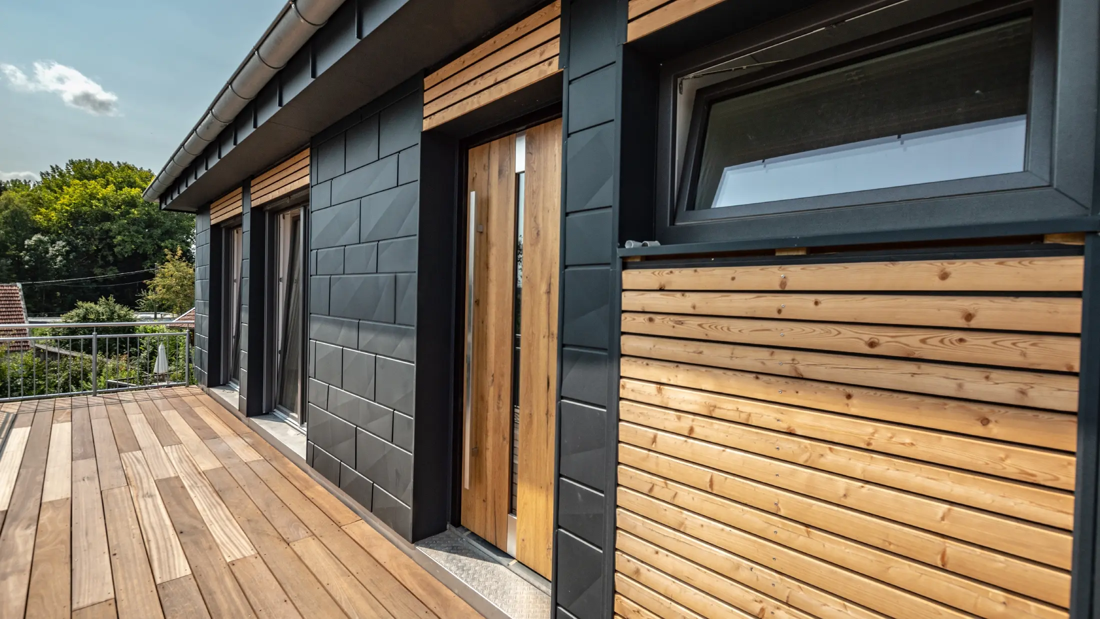 Fasaddesign genom att blanda materialen aluminium - PREFA Siding.X i antracit - och horisontella träbrädor.