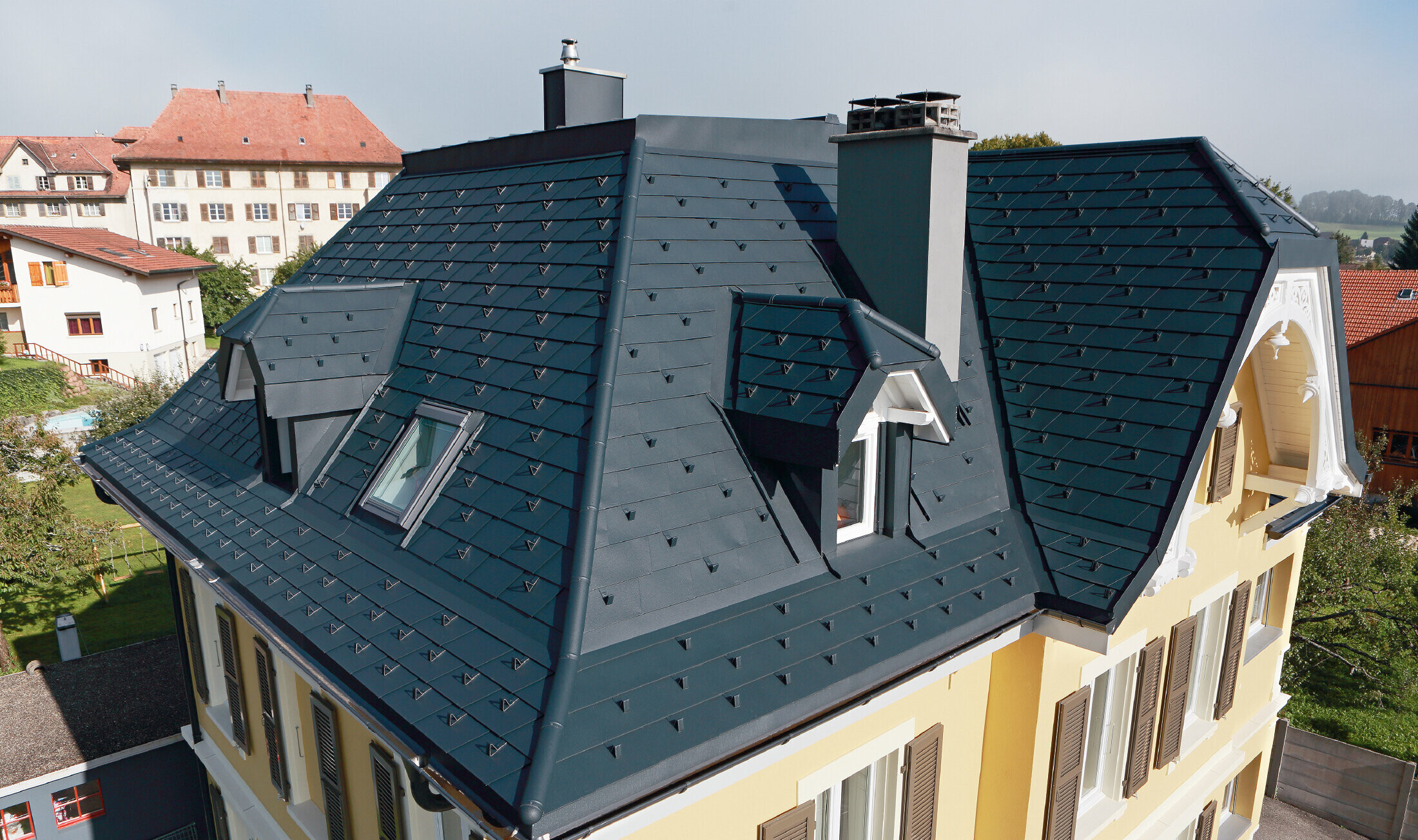 Villa i Schweiz med tak med många vinklar och takkupor; taket är täckt med aluminiumshingel från PREFA i P.10 antracit