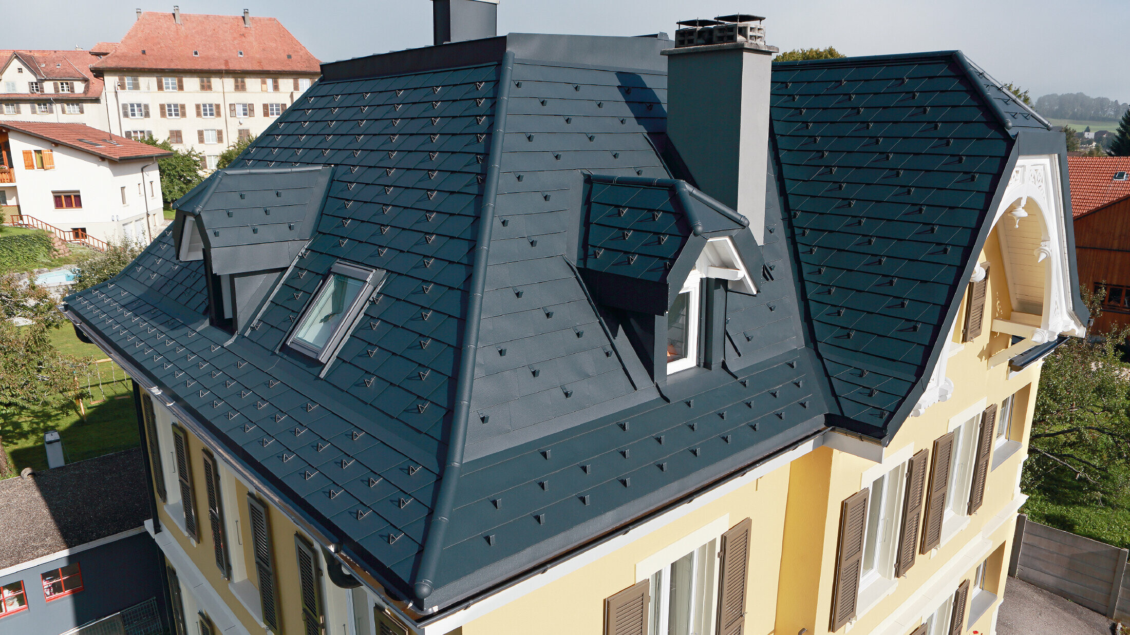 Villa i Schweiz med tak med många vinklar och takkupor; taket är täckt med aluminiumshingel från PREFA i P.10 antracit