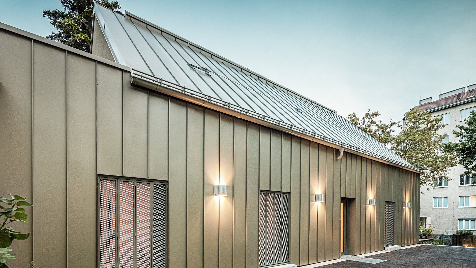 Bilden visar en närbild av Atelier Comploj med fasad och tak av PREFALZ i kulören P.10 Prefabrons.