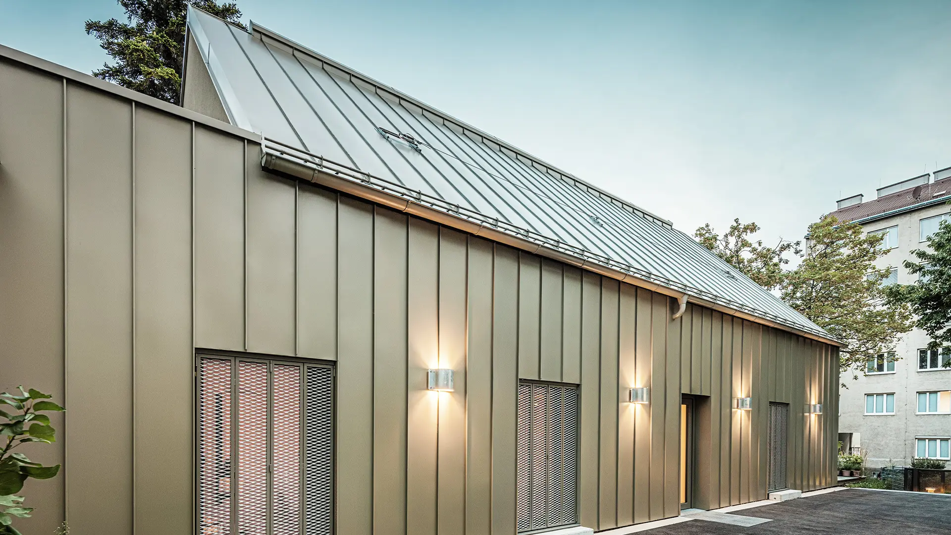 Bilden visar en närbild av Atelier Comploj med fasad och tak av PREFALZ i kulören P.10 Prefabrons.