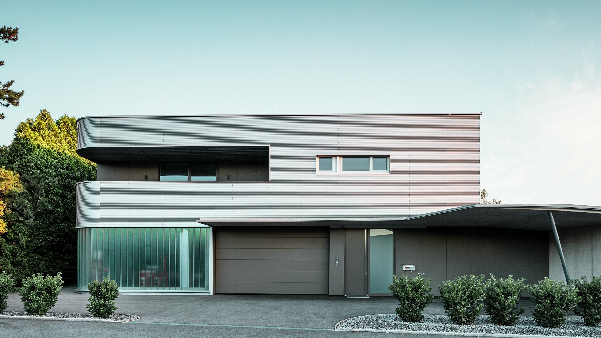 Modernt bostadshus med valsblank PREFA vågprofilsfasad med garage i dagsljus.