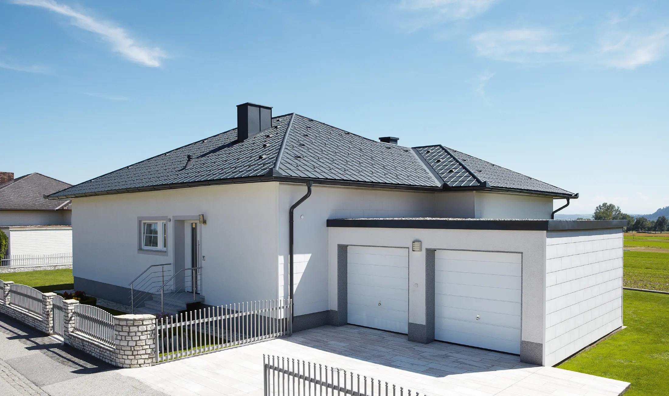 Den nybyggda bungalowen med tälttak täcktes med PREFA takplatta i P.10 antracit. Till höger, fotograferat från gatan, tillkom ett dubbelgarage.