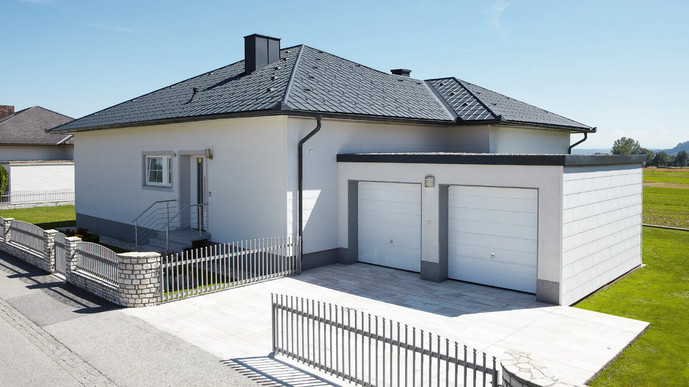 Den nybyggda bungalowen med tälttak täcktes med PREFA takplatta i P.10 antracit. Till höger, fotograferat från gatan, tillkom ett dubbelgarage.