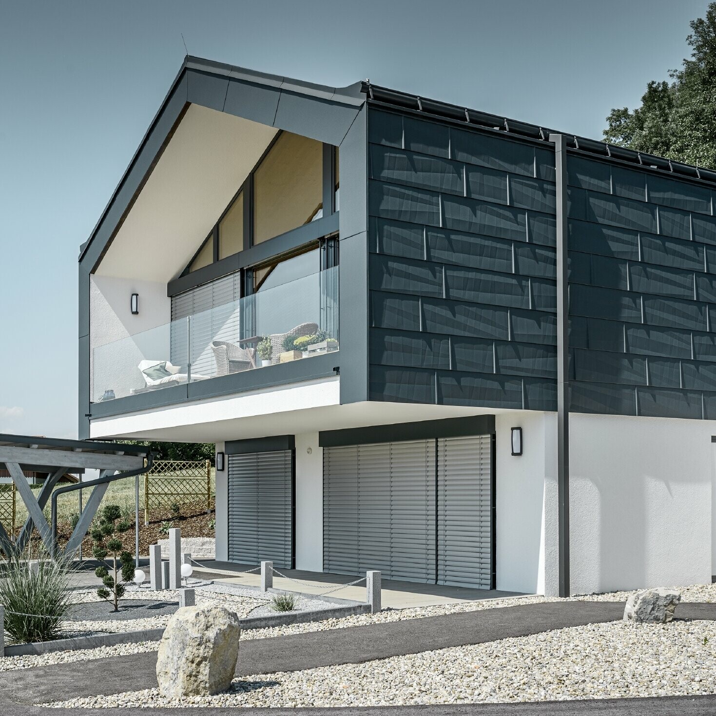 Modernt flerfamiljshus med stora fönsterpartier på framsidan, tak och fasad är täckt med tak- och fasadpanel FX.12 i antracit från PREFA