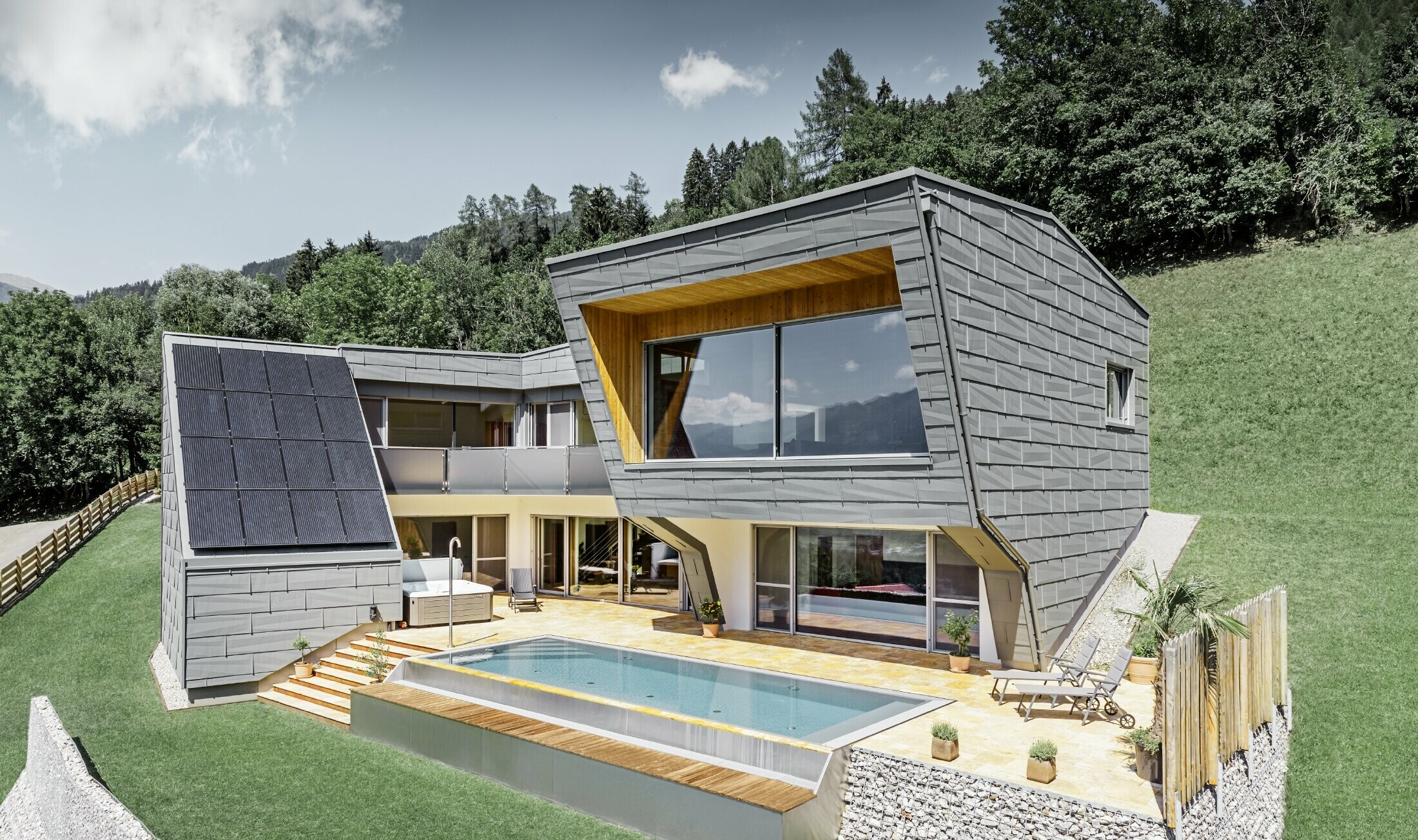 Det moderna huset på en sluttning med pool kläddes med fasadpanelen FX.12 från PREFA i P.10 ljusgrå.