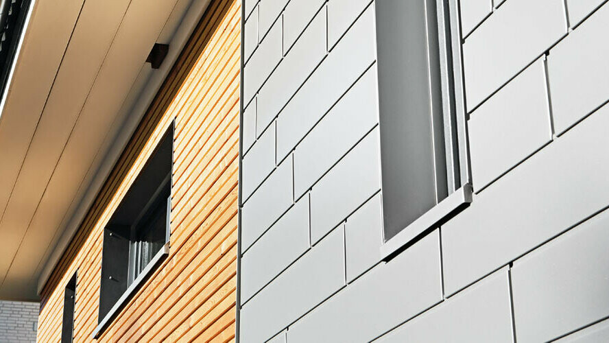 PREFA fasadpaneler i grått aluminium i kombination med en träfasad. Horisontell läggning, förskjutna fogar.