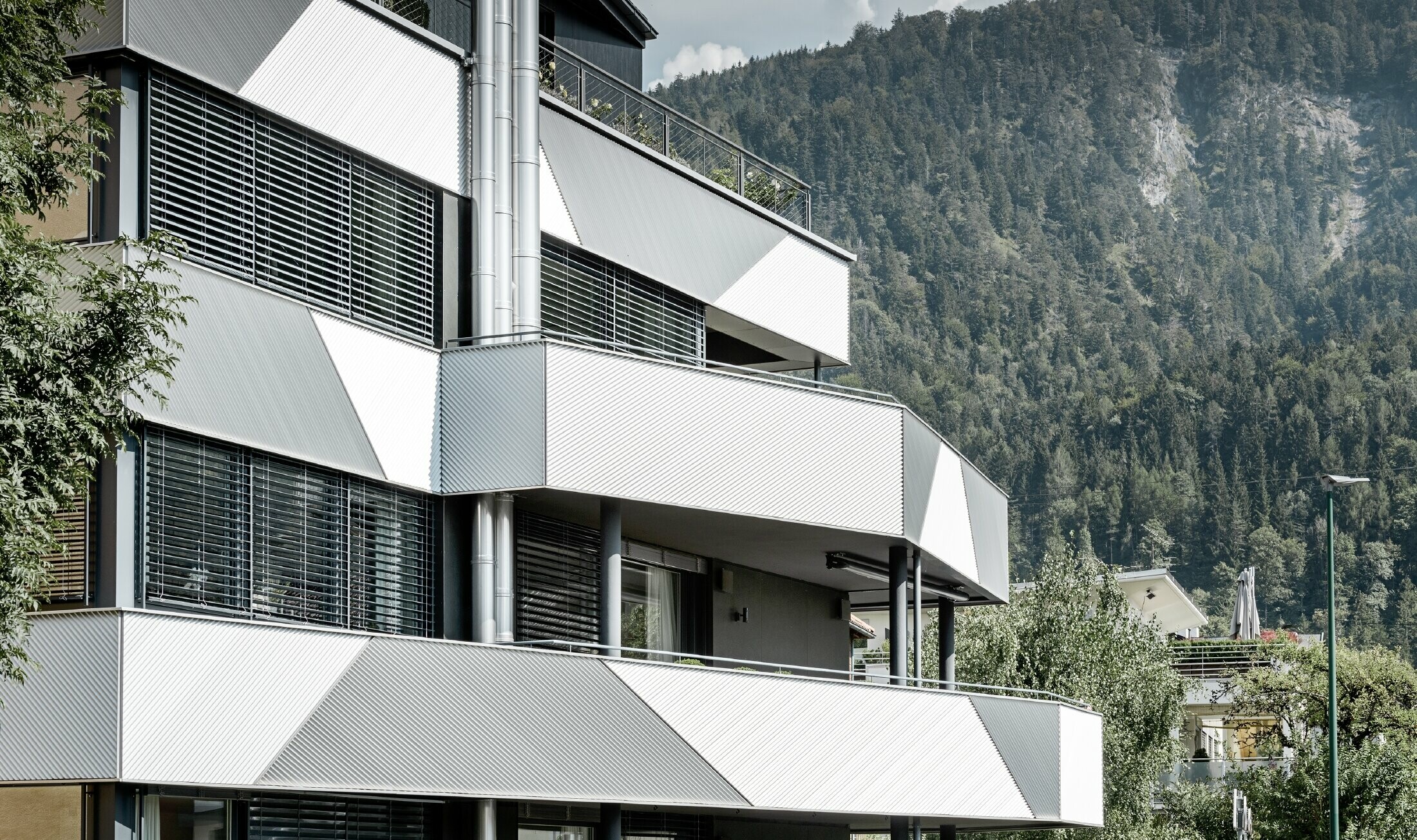 Fasaddesign för ett flerfamiljshus med balkonger och altaner med sicksackprofil från PREFA, diagonalt monterade.