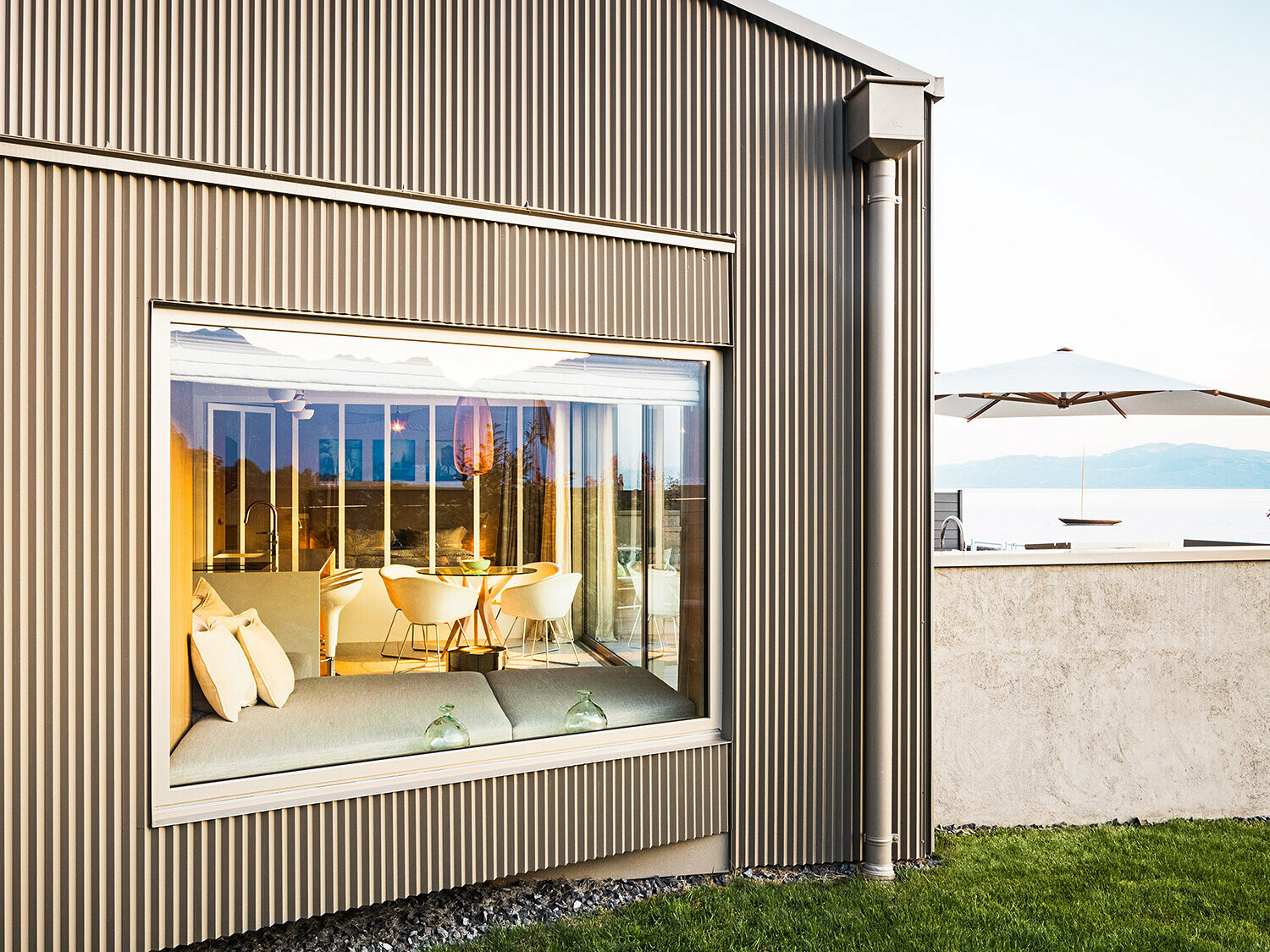 Sidovy av byggnaden med tandad aluminiumfasad, en del av det upplysta interiören syns.